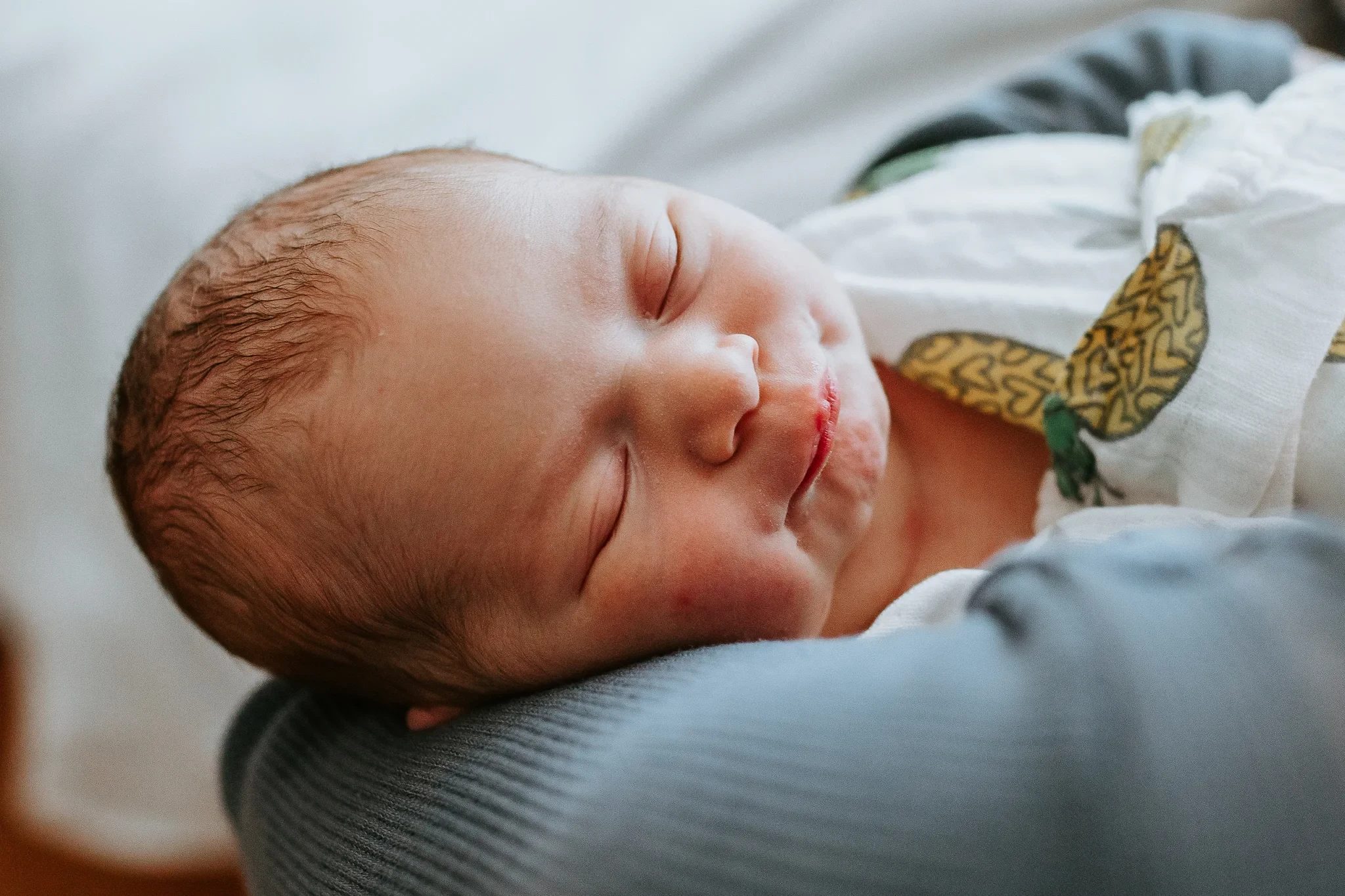 Baby sleeps peacefully across an adult’s forearm