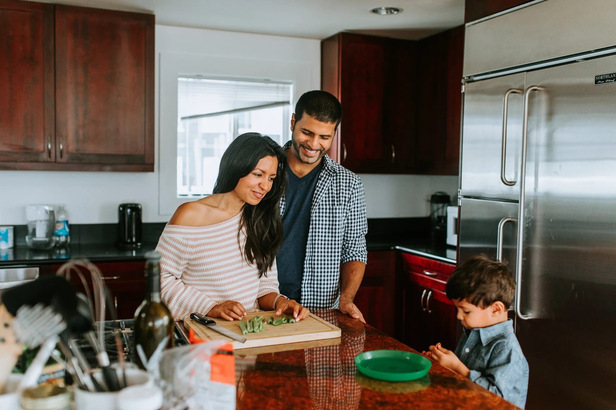 Family gathers around a kitchen counter while preparing food